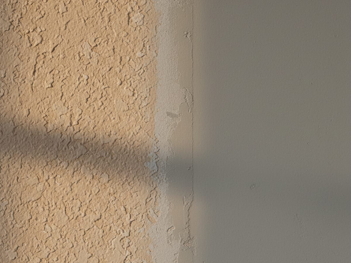 Close-up of a textured drywall surface showing orange peel texture alongside a freshly patched area with no texture yet applied